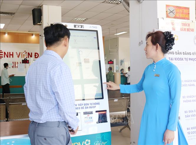 Nhân viên Bệnh viện Đa khoa Ninh Thuận (phường Ninh Chử hướng dẫn người dân thực hiện thủ tục khám bệnh tại kiosk y tế thông minh. (Ảnh: Nguyễn Thành/TTXVN)